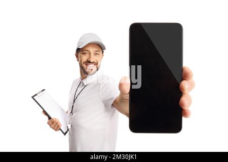 Allenatore sportivo con un fischio che tiene in mano una clipboard e mostra uno smartphone isolato su sfondo bianco Foto Stock