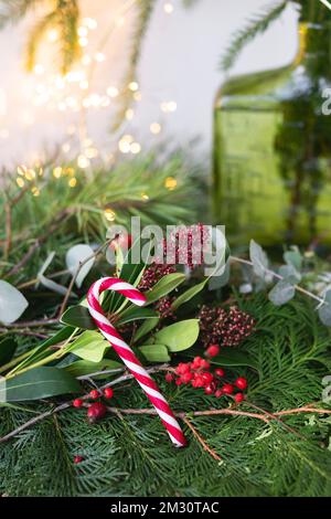 Sfondo verde di foglie viventi e rami, rosso caramella di Natale. La composizione di Capodanno, un'apertura pronta all'uso. Capodanno e festa di Natale Foto Stock