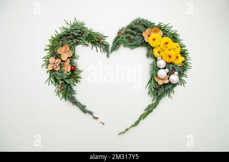 Composizione di Natale. Simbolo del cuore di pino, cipresso, rami di thuja, palle, bacche e decorazioni in legno. Natale, inverno, Capodanno c Foto Stock