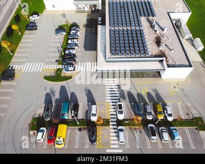 Parcheggio di fronte ad un moderno edificio di uffici con pannelli solari sul tetto Foto Stock