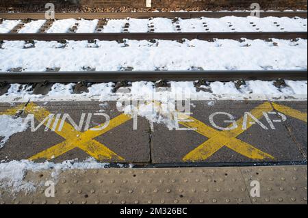 Stazione di London Fields, Hackney, Londra. Inghilterra; Regno Unito. In una giornata di sciopero in treno, i binari e la piattaforma dicono "Mind the Gap" nella neve. Foto Stock
