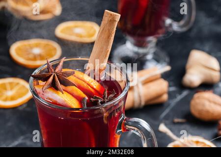 Natale caldo VIN brulé in un bicchiere con spezie e agrumi. VIN brulé con cannella, anice e arancia Foto Stock