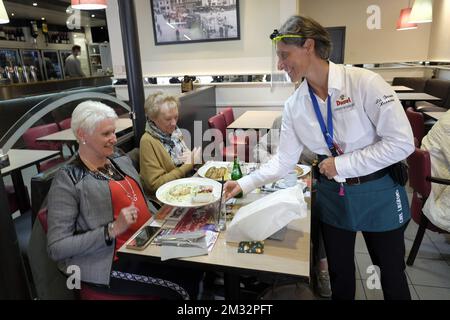 L'immagine mostra un cameriere che indossa uno schermo facciale che serve cibo ai clienti in un cafe' ad Hannut, Lunedi' 08 Giugno 2020. Oggi è il primo giorno della fase 3 del definement. Il settore dell'oreca può riaprirsi, ma deve applicare regole di allontanamento sociale nelle proprie imprese. FOTO DI BELGA ERIC LALMAND Foto Stock