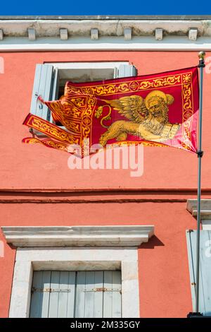 Bandiera del leone di Venezia, veduta di una bandiera del Leone di San Marco - emblema della città e del comune di Venezia - in una strada sull'isola veneziana di Chioggia Foto Stock