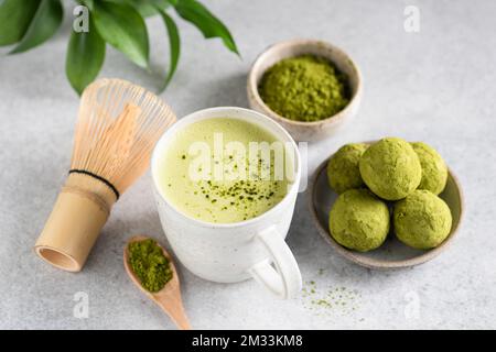 Tè verde Matcha e tartufi di cioccolato Matcha su sfondo grigio. Cibo vegano verde Foto Stock