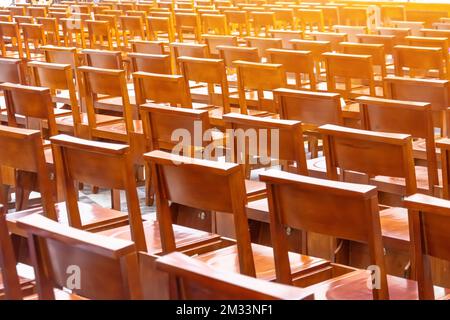 Sedie nella chiesa nella sala di preghiera, poltrone di legno marrone in file dietro Foto Stock