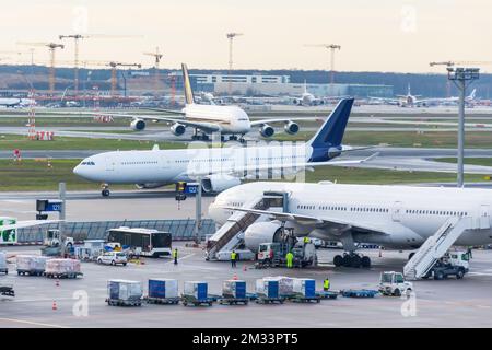 Vista su un campo aereo occupato con aerei e veicoli di servizio. Vista dell'aeroporto internazionale con aerei, passerelle, camion e attrezzature di servizio. Viaggi e. Foto Stock