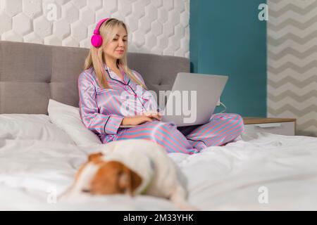 Una ragazza con un cane che guarda un film su un computer portatile con le cuffie. Animali domestici e amici animali domestici per le persone Foto Stock