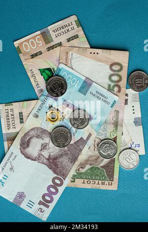 Moneta contanti valuta Ucraina hryvnia cinquecento hryvnia migliaia fatture e monete denaro guadagni concetto dollari su uno sfondo blu Foto Stock