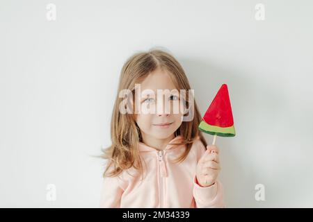 Carina bambina con cocomero lollipop. Sfondo bianco. Concetto di umore estivo e di vacanza Foto Stock