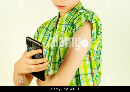 Trattamento del diabete. Controllo del paziente diabetico. Ragazzo adolescente che controlla il livello di glucosio con un sensore remoto. Monitoraggio dei livelli di glucosio senza sangue. Medico Foto Stock