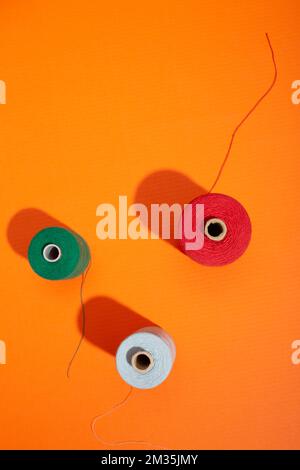 Tre bobine con fili colorati su sfondo colorato Foto Stock