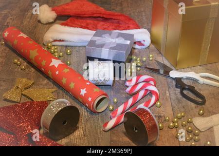 Nastri colorati, scatole regalo, carta da imballaggio su un tavolo di legno. Preparandosi per Natale. Attributi per i regali Foto Stock