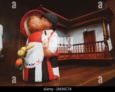 A cute small statuette of a couple in red, white, black clothes kissing Stock Photo