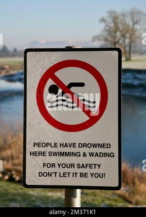 Un cartello sulla riva del fiume che identifica i pericoli del nuoto nel fiume Ribble a Ribchester, Lancashire, Regno Unito, Europa Foto Stock