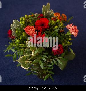 bouquet floreale di gerberie rosse, garofani e verde professionalmente fatto primo piano Foto Stock