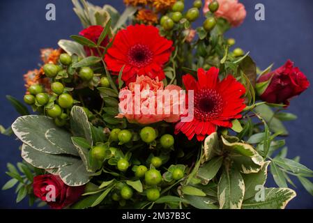 bouquet floreale di gerberie rosse, garofani e verde professionalmente fatto primo piano Foto Stock