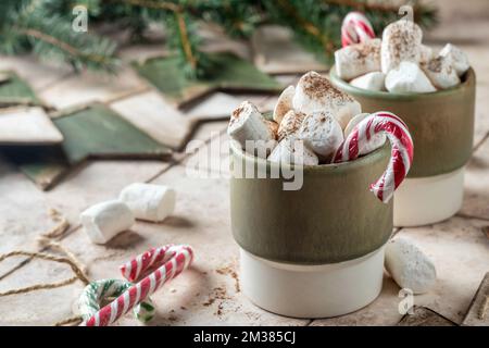 Tazza di cioccolata calda o cacao con marshmallow e albero di natale su sfondo piastrellato beige con bandiere di legno decorazione ghirlanda. Atmosfera festosa, christm Foto Stock