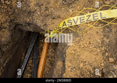 L'immagine mostra un nastro che legge 'Glasvezel' durante l'installazione di fibra ottica in una zona residenziale di Gand, martedì 08 febbraio 2022. Proximus ha chiesto al governo di stanziare fondi per ottenere Internet a velocità più elevate negli angoli rurali del paese. L'azienda sta investendo miliardi per collegare almeno il 70% del paese alla sua nuova rete in fibra entro il 2028. Attualmente Proximus sta completamente estraendo la fibra in varie città. Questa tecnologia moderna rende possibile la connessione a Internet più veloce. L'azienda, che è metà di proprietà del governo, mira ad estendere i nuovi cavi ad almeno 4. Foto Stock