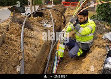 L'immagine mostra l'installazione di fibre ottiche in una zona residenziale di Gand, martedì 08 febbraio 2022. Proximus ha chiesto al governo di stanziare fondi per ottenere Internet a velocità più elevate negli angoli rurali del paese. L'azienda sta investendo miliardi per collegare almeno il 70% del paese alla sua nuova rete in fibra entro il 2028. Attualmente Proximus sta completamente estraendo la fibra in varie città. Questa tecnologia moderna rende possibile la connessione a Internet più veloce. L'azienda, che è metà di proprietà del governo, mira ad estendere i nuovi cavi ad almeno 4,3 milioni di case, o almeno 70 perc Foto Stock