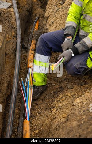 L'immagine mostra l'installazione di fibre ottiche in una zona residenziale di Gand, martedì 08 febbraio 2022. Proximus ha chiesto al governo di stanziare fondi per ottenere Internet a velocità più elevate negli angoli rurali del paese. L'azienda sta investendo miliardi per collegare almeno il 70% del paese alla sua nuova rete in fibra entro il 2028. Attualmente Proximus sta completamente estraendo la fibra in varie città. Questa tecnologia moderna rende possibile la connessione a Internet più veloce. L'azienda, che è metà di proprietà del governo, mira ad estendere i nuovi cavi ad almeno 4,3 milioni di case, o almeno 70 perc Foto Stock