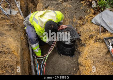 L'immagine mostra l'installazione di fibre ottiche in una zona residenziale di Gand, martedì 08 febbraio 2022. Proximus ha chiesto al governo di stanziare fondi per ottenere Internet a velocità più elevate negli angoli rurali del paese. L'azienda sta investendo miliardi per collegare almeno il 70% del paese alla sua nuova rete in fibra entro il 2028. Attualmente Proximus sta completamente estraendo la fibra in varie città. Questa tecnologia moderna rende possibile la connessione a Internet più veloce. L'azienda, che è metà di proprietà del governo, mira ad estendere i nuovi cavi ad almeno 4,3 milioni di case, o almeno 70 perc Foto Stock