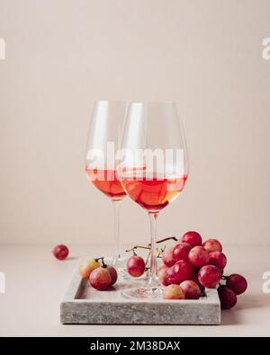 Due bicchieri di vino rosato e un mazzo di uve rosse. Foto Stock
