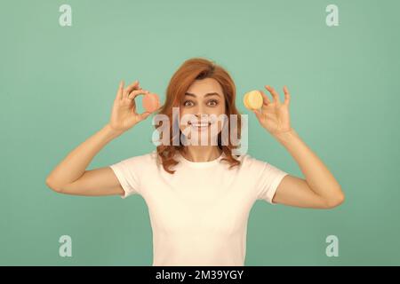 signora sorpresa tenere dolce macaron biscotto francese su sfondo blu Foto Stock