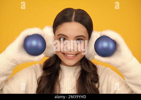 Buon natale e Felice Anno Nuovo. Bambino in abiti invernali. Ragazza teen con palla decorativa. Faccia felice, emozioni positive e sorridenti della ragazza adolescente. Foto Stock