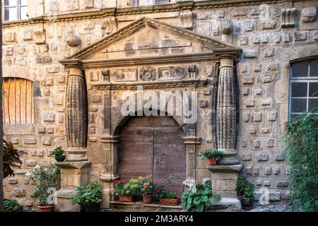 Primo piano di una vecchia porta di legno su un muro di pietra scolpita nella città di Florac in Francia Foto Stock