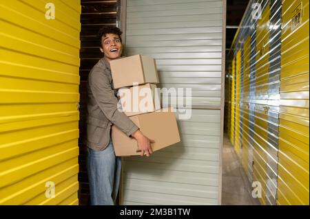 Giovane uomo che trasporta molte scatole pesanti Foto Stock