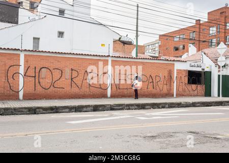 Una vecchia donna che cammina di fronte a un grande graffito in spagnolo. Significa 6402 motivi per marzo. una rifference agli omicidi non ufficiali commessi dalla colombia Foto Stock