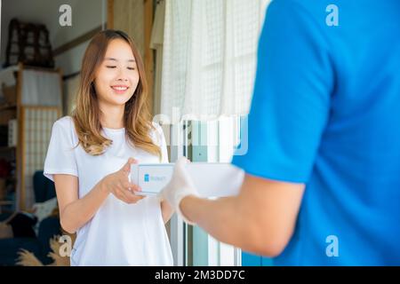 La giovane donna asiatica malata riceve la scatola della farmacia di pronto soccorso della medicina dal servizio di consegna dell'ospedale Foto Stock