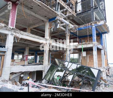 Edificio cittadino in un processo di demolizione pianificato con struttura esposta e macerie sul terreno. Foto Stock