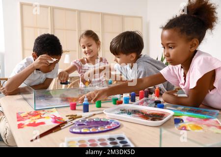 Bambini piccoli dipingendo sull'acqua durante la lezione di master a Ebru in officina Foto Stock