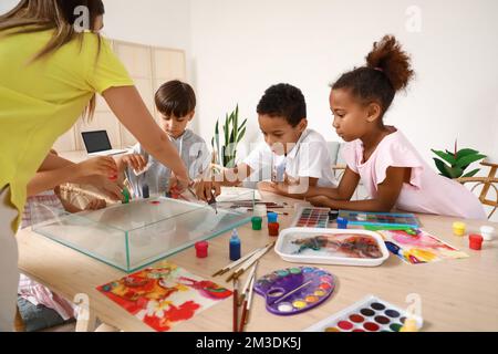 Bambini piccoli con insegnante di pittura sull'acqua durante la master class a Ebru in laboratorio Foto Stock