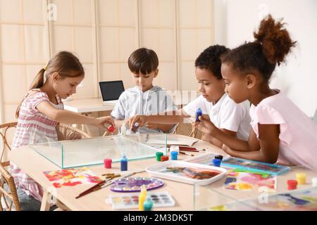 Bambini piccoli dipingendo sull'acqua durante la lezione di master a Ebru in officina Foto Stock