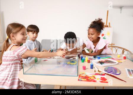 Bambini piccoli dipingendo sull'acqua durante la lezione di master a Ebru in officina Foto Stock