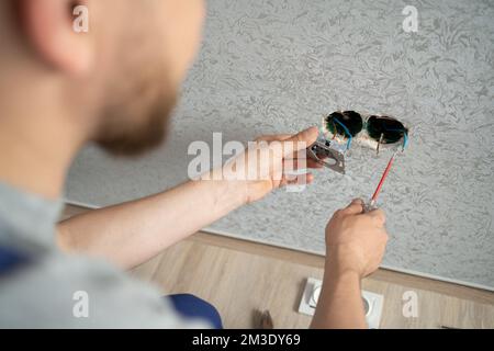 l'elettricista collega le prese ai cavi elettrici a parete, lavora sull'installazione delle prese elettriche. Foto Stock