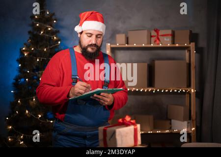 Piccole e medie imprese start up concetto giovane imprenditore start-up, indossando cappello babbo natale e tute da lavoro, prende uno stand in un ufficio a casa riempimento Foto Stock