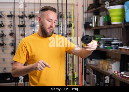 Uomo acquirente scelta di accessori per la pesca nel negozio di sport. Spazio di copia Foto Stock