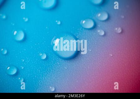 Gocce d'acqua su sfondo blu con un gradiente rosa.struttura fluida in toni blu freddi.gocce macro impostate Foto Stock