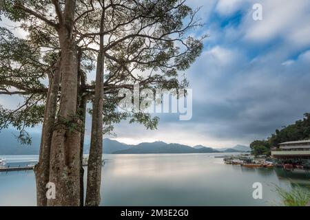 Mattina presto, alcune barche sul lago. Cielo blu, montagne e alberi verdi. Molo di Chaowu, area panoramica nazionale del lago Sun Moon. Contea di Nantou, Taiwan Foto Stock