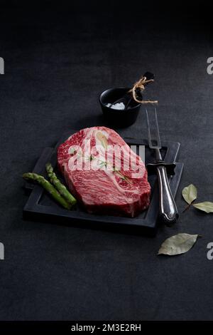 manzo fresco sul piatto di taglio con fondo nero e molti ingredienti Foto Stock