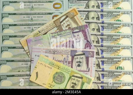 Arabia Saudita banconote riyal oltre un closeup di banconote da 100 dollari USA Foto Stock