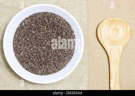 Colazione sana, semi di chia o superfood in ciotola bianca su panno di lino con cucchiaio di legno. Foto Stock