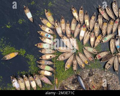 Dhaka, Bangladesh. 15th Dec, 2022. Una flotta di barche in legno tifosi intorno ai loro ormeggi nel fiume Buriganga a Dhaka, Bangladesh. Il fiume è ampiamente utilizzato per trasportare merci, prodotti e persone. Si stima che circa 50.000 pendolari attraversano il Buriganga da Keraniganj per lavorare a Dhaka, e molti prendono barche. Centinaia di piccole imbarcazioni, chiamate 'Dinghy Noukas', sono ormeggiate nel porto fluviale di Dhaka, la capitale del Bangladesh. In essi, i ferrieri trasportano lavoratori, merci e turisti attraverso il fiume Buriganga ogni giorno. Credit: Joy Saha/Alamy Live News Foto Stock