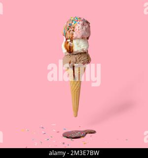 divertente concetto creativo di cono di wafer volante con gelato coperto, cosparso di spruzzi e versato con glassa di cioccolato su sfondo rosa Foto Stock