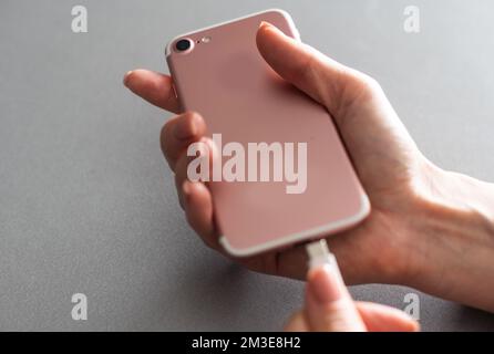 Consente di caricare lo smartphone su sfondo bianco. Vista dall'alto. Caricare il telefono. Foto Stock