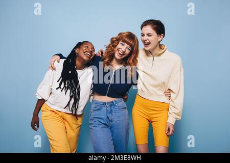 Amici femminili diversi ridendo e avendo un buon tempo mentre abbracciandosi l'un l'altro. Gruppo di giovani donne felici che si godono mentre si levano in piedi di nuovo Foto Stock